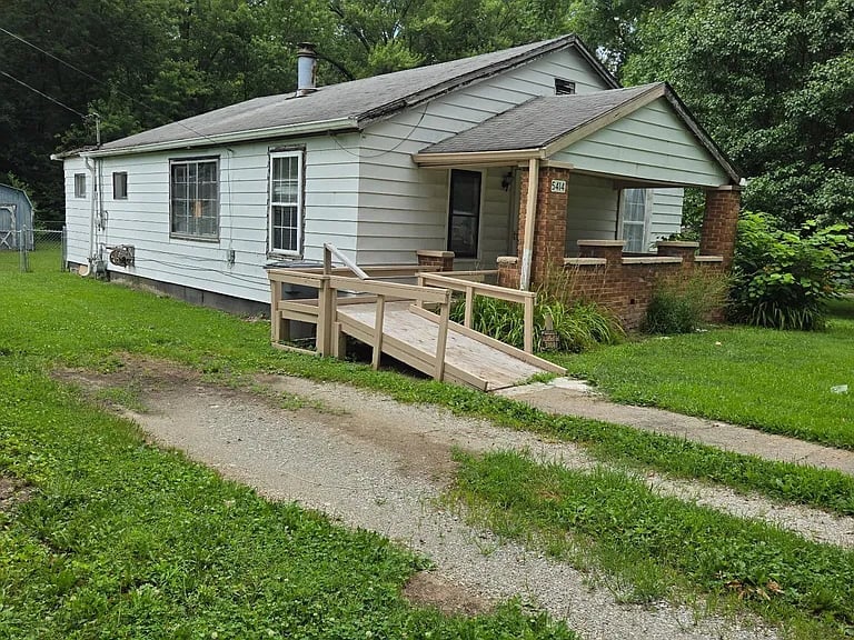 5414 E Orange St — single-story home with white siding and brick porch, under rehabilitation